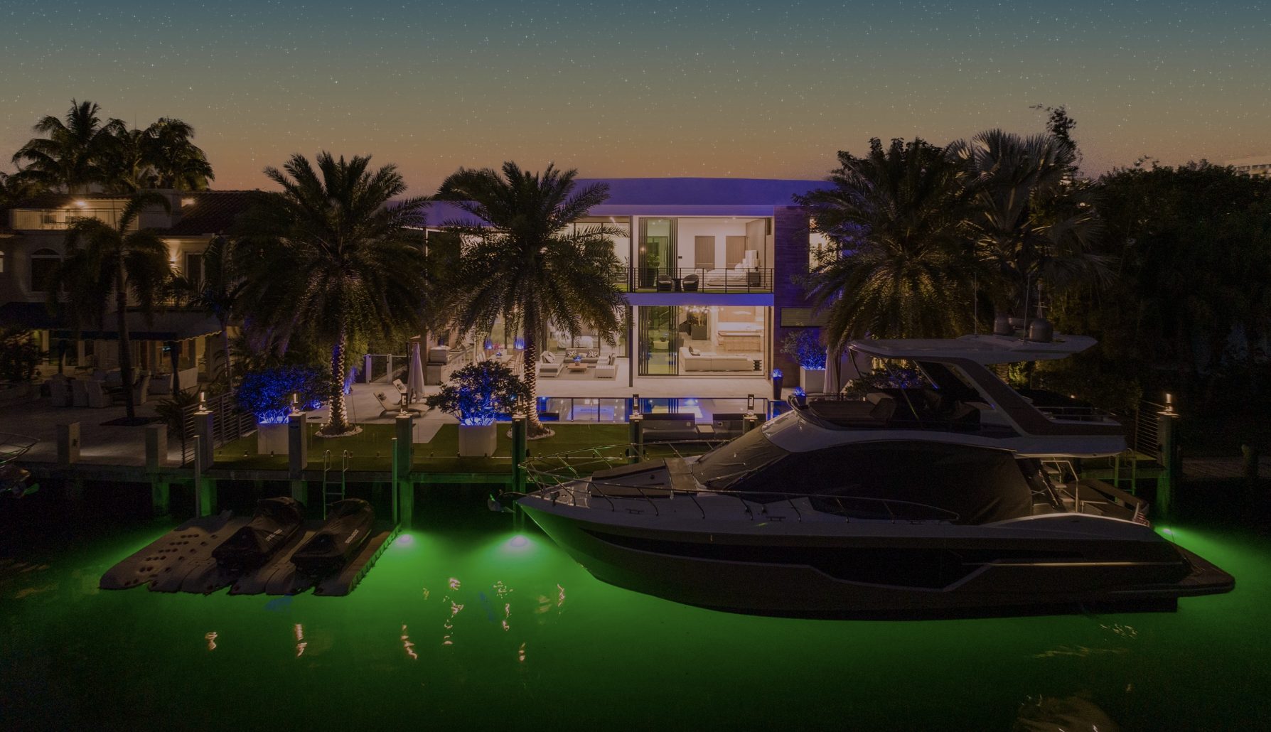 A waterfront estate and yacht at night